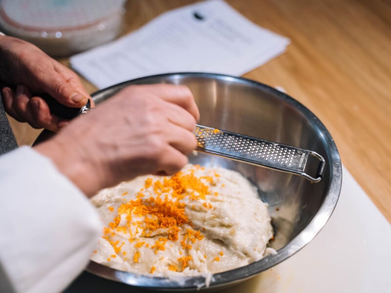 Close up on hands grating citrus zest into a dish
